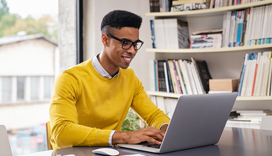 Man in a yellow sweater using a laptop